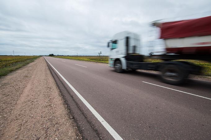 Een vrachtwagen rijdt op een Belgische snelweg in het midden van de velden
