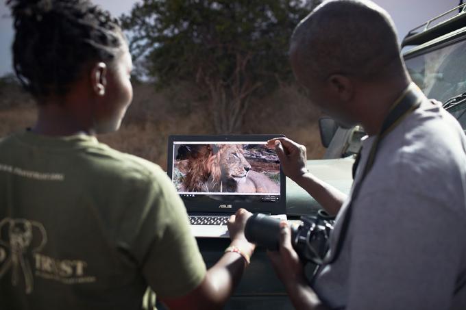 Een anti-stroperij patrouille bekijkt leeuwenfoto's op een computer.