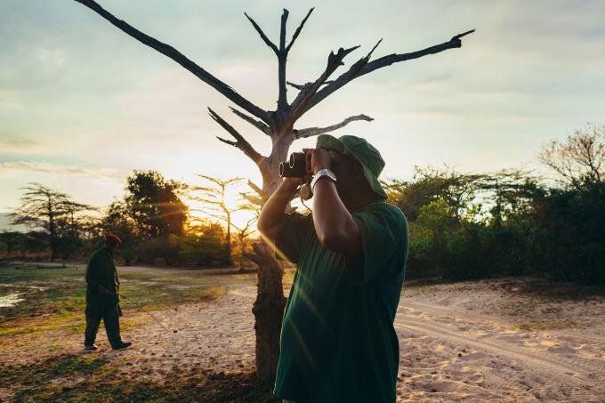 Vrijwilliger voor het behoud van de neushoorn gebruikt een verrekijker om de savanne te observeren om stroperij te stoppen